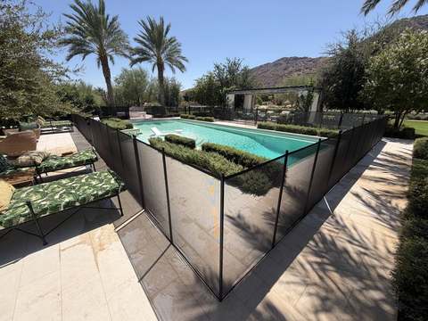 Removable mesh pool fence around a pool with landscaping